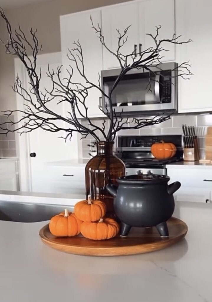Witch-inspired Halloween tiered tray decorated with potion bottles, faux cobwebs, black cat figurines, and spell books. Credit: Mrs. Alonzo, www.slowestuff.com