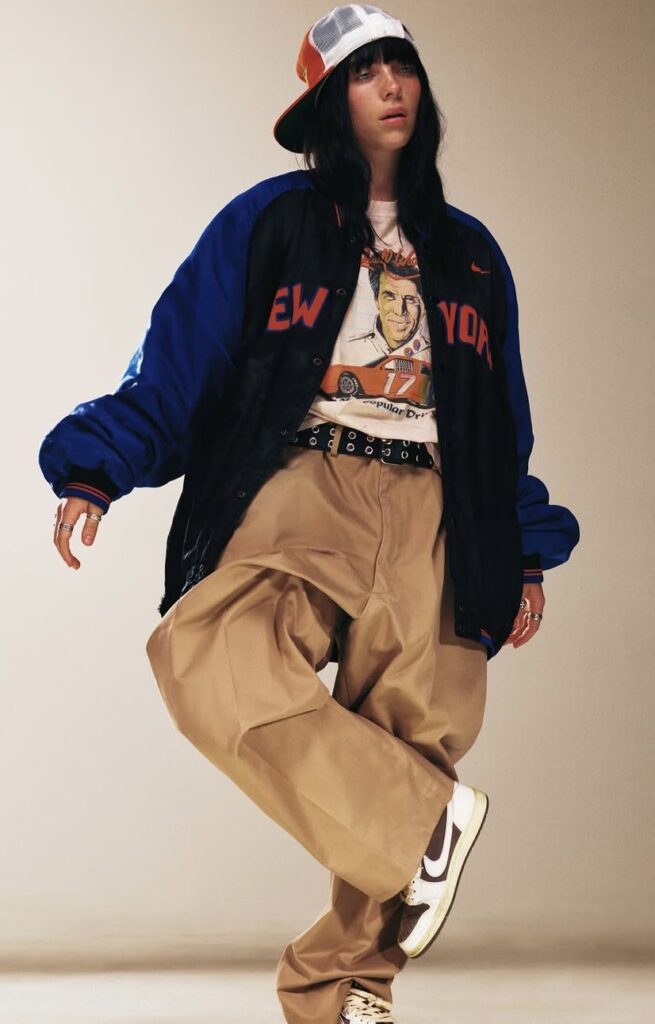 Billie Eilish wearing oversized bomber jacket and cargo pants, showcasing her signature baggy street style. Halloween inspiration from Slowestuff.com