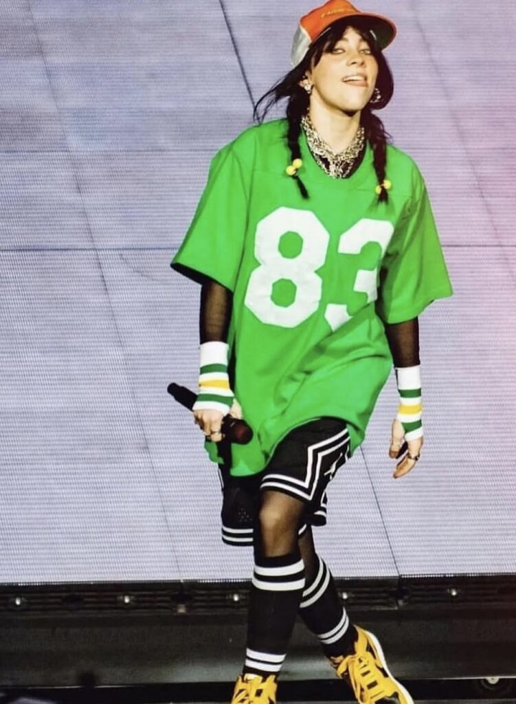 Billie Eilish performing in a green soccer jersey and gym shorts, a fun and sporty Halloween costume option. Photo credit: @billieeilish on Instagram via Slowestuff.com