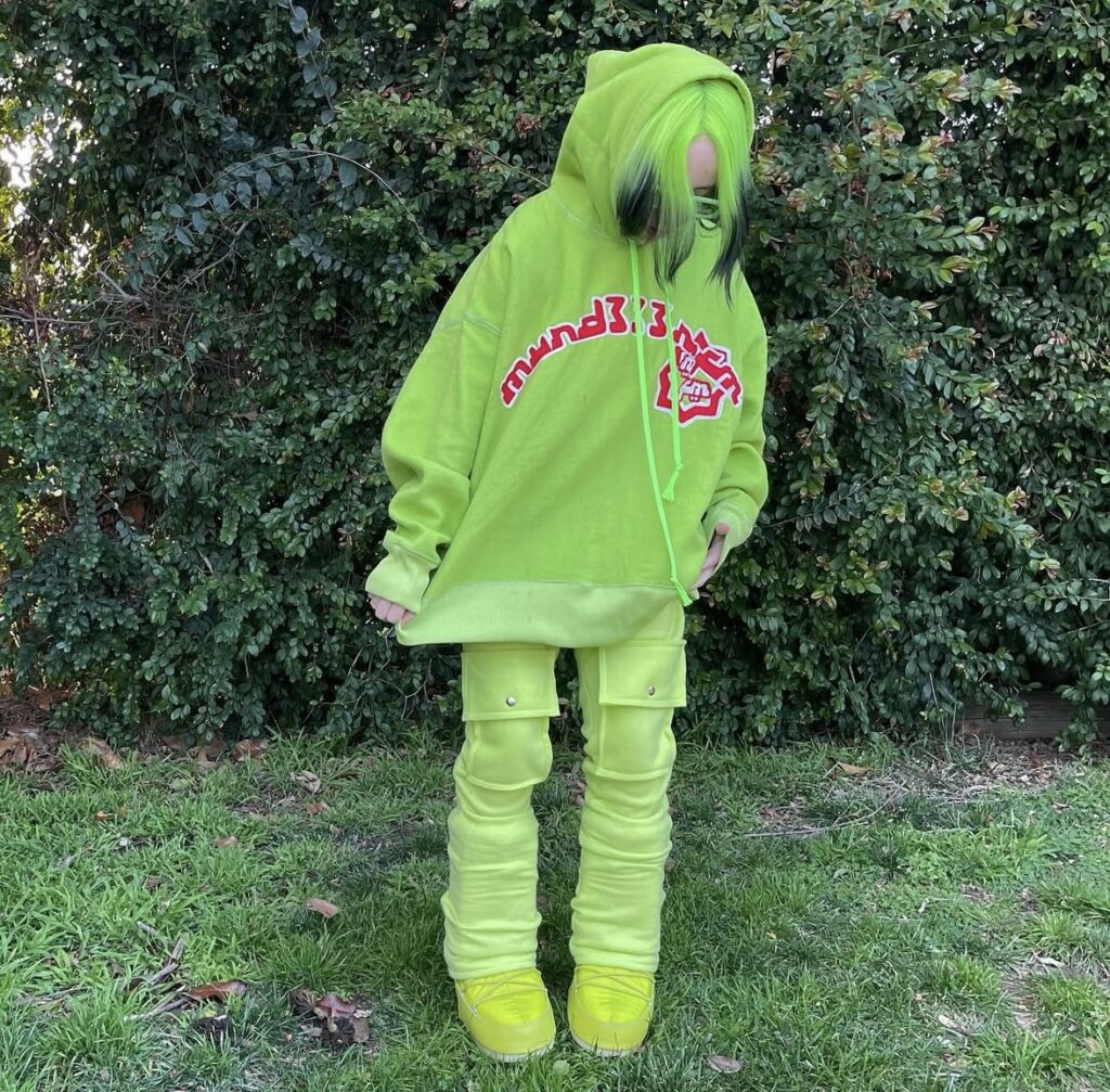 Billie Eilish in a neon green oversized hoodie and pants, a signature Billie look for Halloween costume inspiration. Photo credit: @billieeilish on Instagram via Slowestuff.com