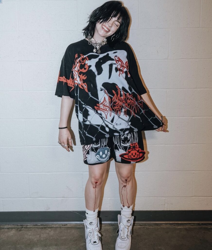Billie Eilish rocking silver chain accessories, bike shorts, and a bold graphic tee, showcasing edgy Halloween costume inspiration. Photo credit: @billieeilish on Instagram via Slowestuff.com