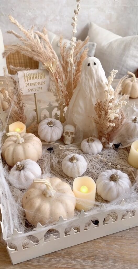 All-neutral tiered tray decorated with wooden ghosts, beige pumpkins, and natural beaded garland for a subtle, earthy Halloween style. Credit: houseofvandel.
