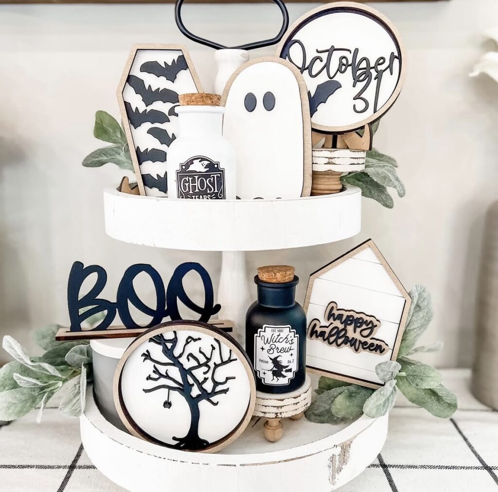 Boo banner draped across a Halloween tiered tray filled with tiny ghost ornaments, faux pumpkins, and little spiders for a playful, festive touch. Credit: hometoheartco.