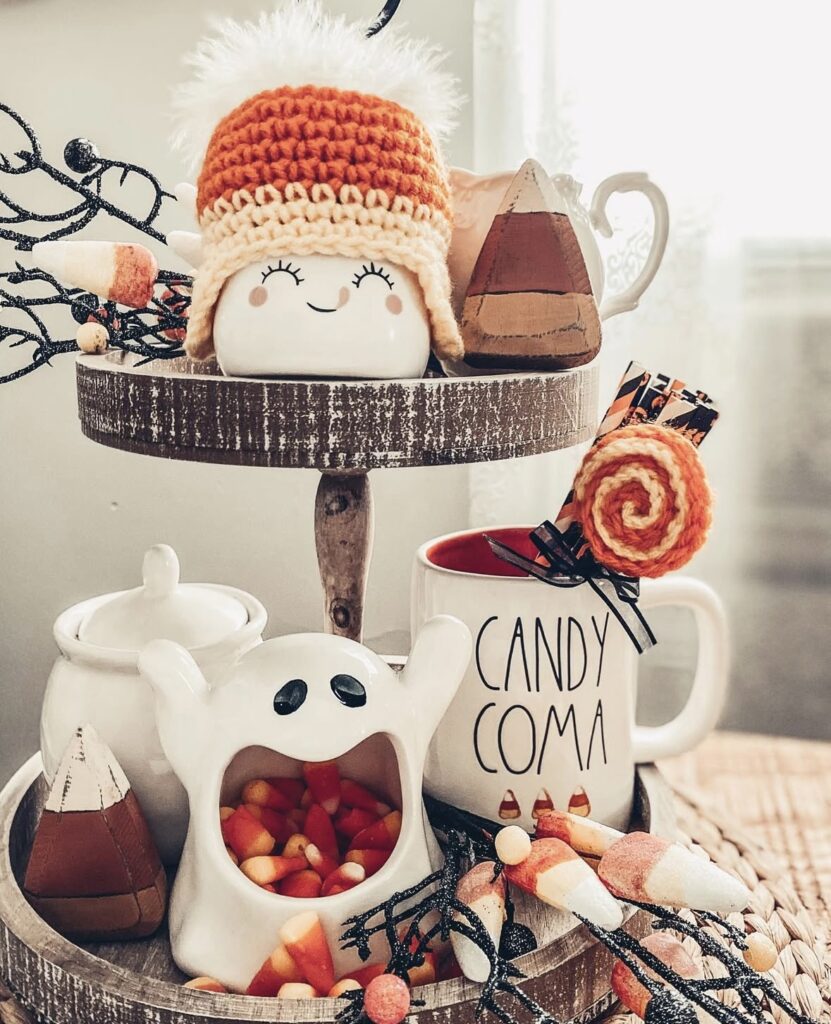 Bright orange and white ghost-themed tiered tray with pumpkin spice mugs, ghost marshmallow decor, and candy corn - major cute Halloween energy! Credit: aguilars.home.