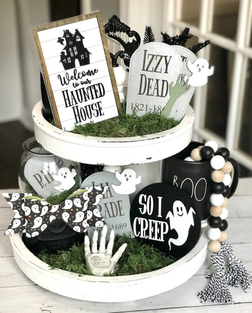 Skeleton graveyard tiered tray decorated in black and white with green grass, with tiny tombstones, skulls, and spooky bone props. Boneyard Halloween tray decor ideas from www.slowestuff.com.