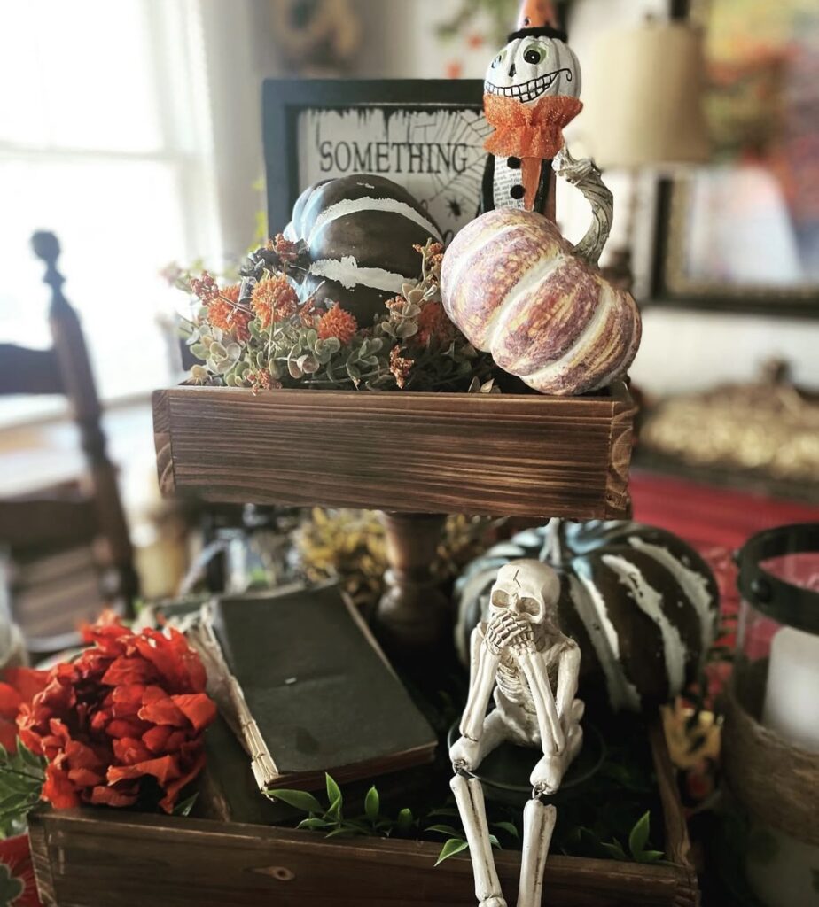 Rectangle shaped Halloween tiered tray styled with skeletons, florals, and pumpkins. See more skeleton tray decor ideas at www.slowestuff.com.