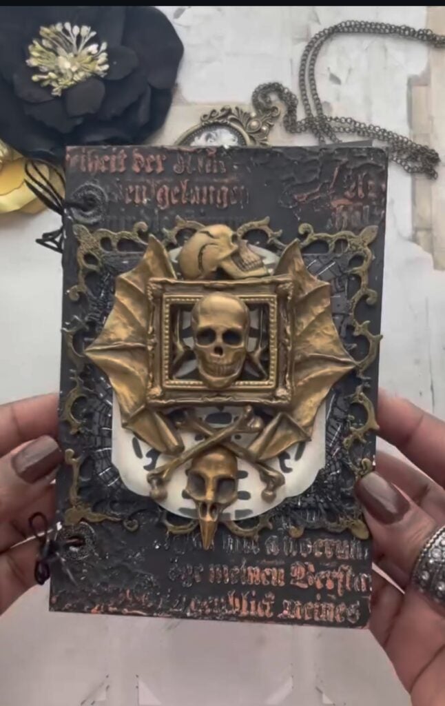 Mixed media journal cover with gold bat wings and skull. Credit: brownbabycraftaholic