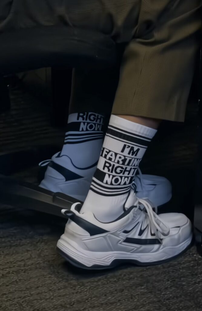 Image of Chit from the TikTok series, wearing socks that say “I’m farting right now,” as part of his Zoom call outfit. Credit: @renshawjay