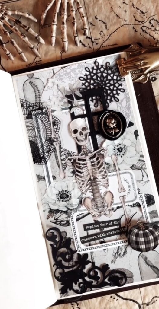 Skeleton scrapbook page with gothic flowers and gold hand clip. Credit: journalzjourney & cheeryletters