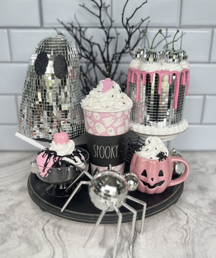 Whimsical Halloween tray decorated with glittery ghosts, felt pumpkins, and candy corn garland for a playful, colorful touch. Credit: bowsandsilos.