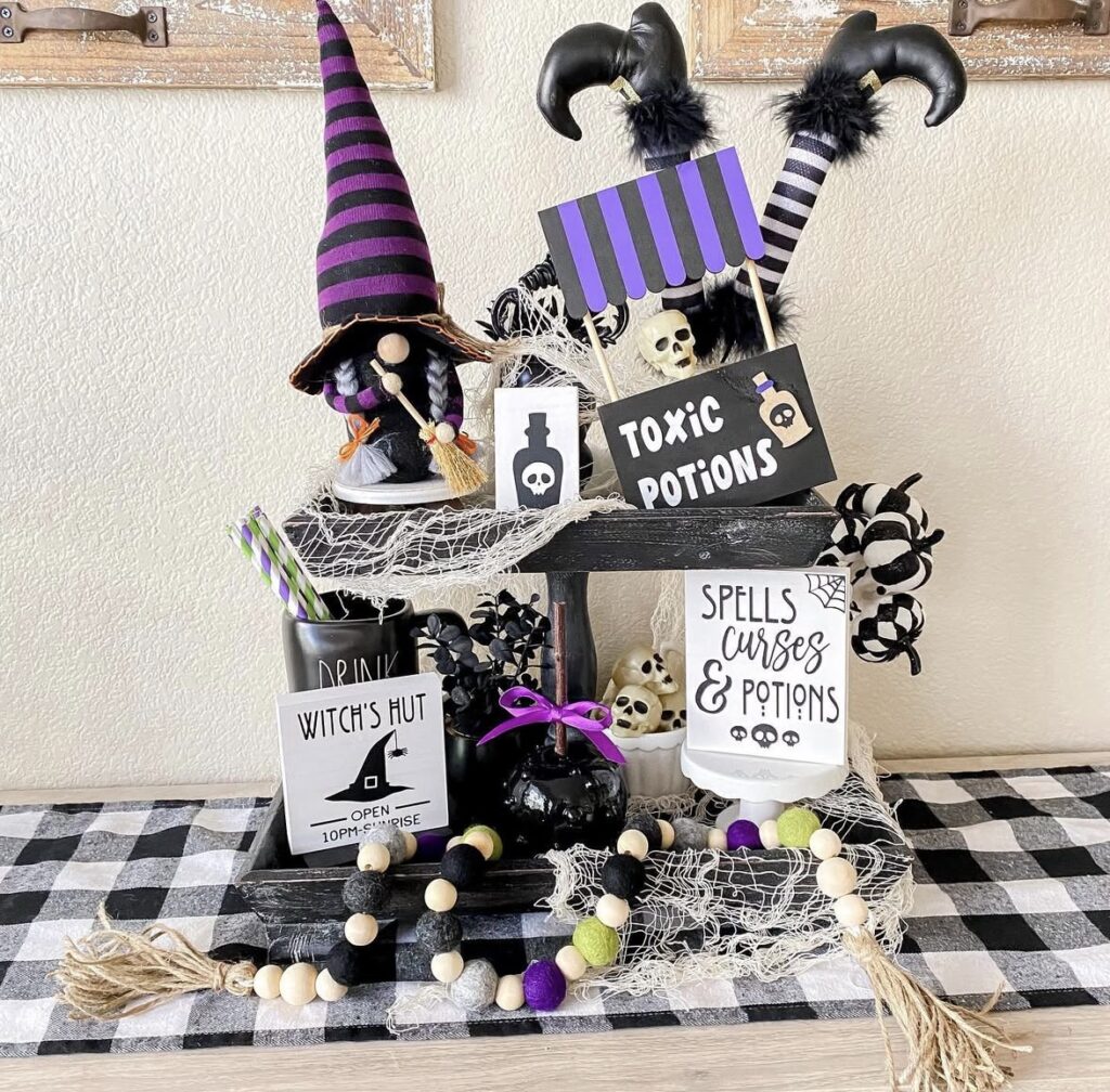 Witch inspired Halloween tiered tray with purple, white, and black styling, witch legs, and witch on a broom with black cat. Credit: allthedayscreation, www.slowestuff.com