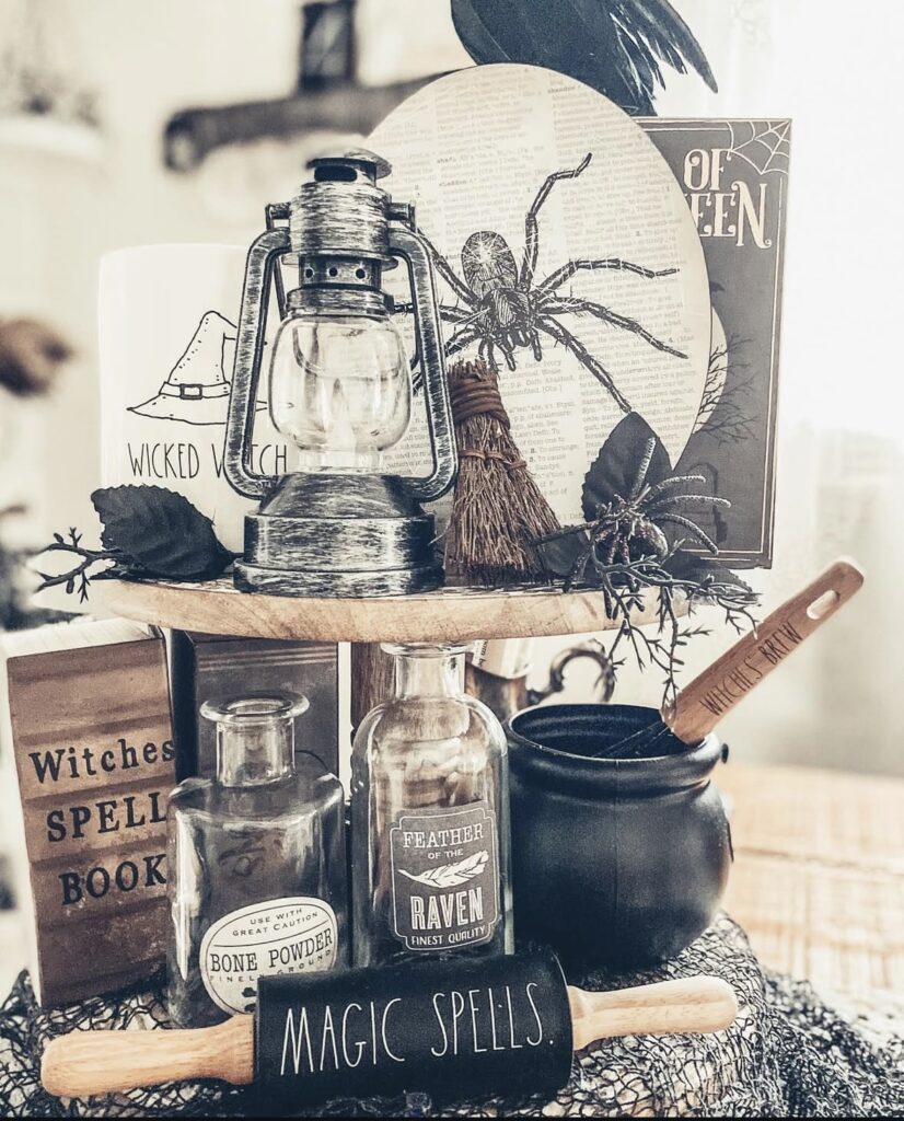 Muted witchcore tray with vintage spell book, lantern, pumpkins, and neutral witchy elements for Halloween. Credit: aguilars.home, www.slowestuff.com