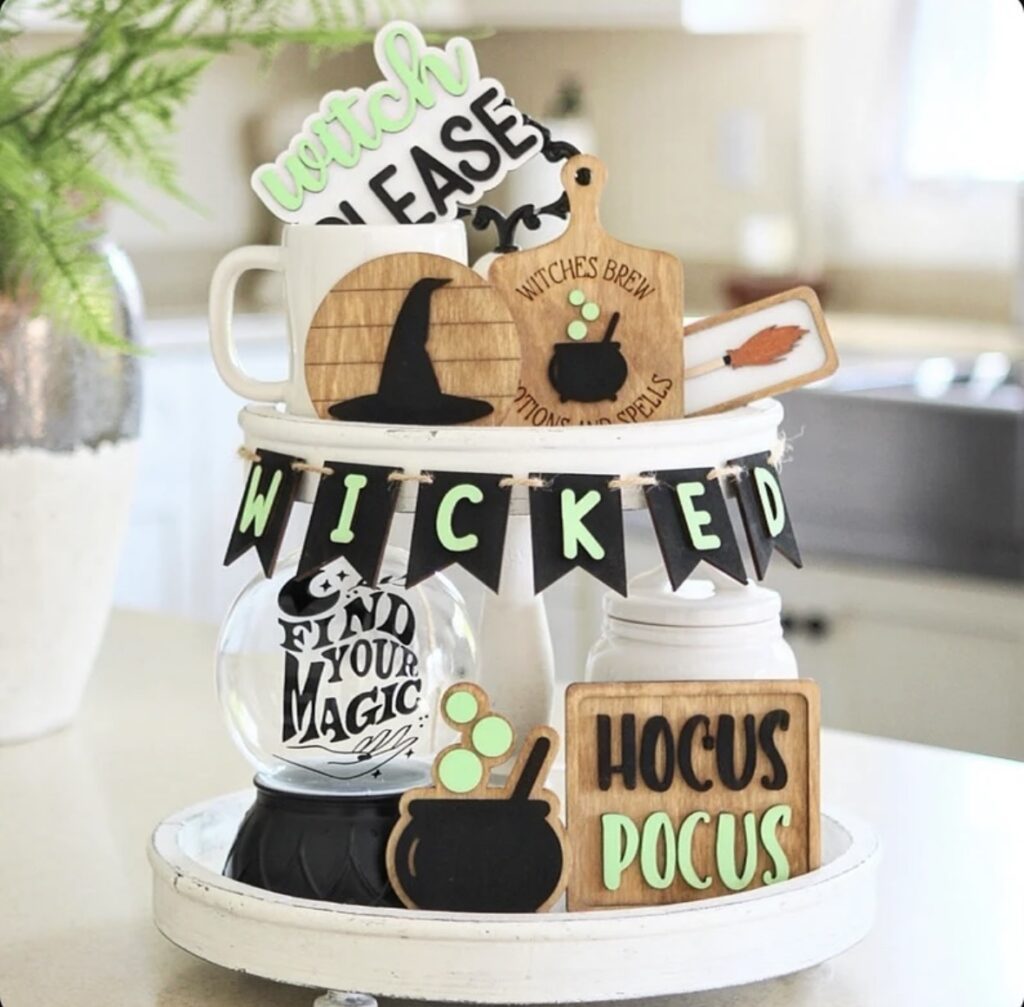 Witchy Halloween tiered tray with rustic wood, green accents, wooden cauldron, crystal ball, and “Wicked” banner. Credit: createbynic, www.slowestuff.com