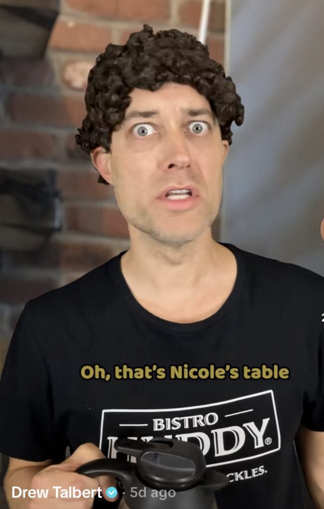 Another viral TikTok screenshot of Bistro Huddy’s character with brown curly wig and Bistro Huddy shirt. Costume idea for Halloween 2025.
