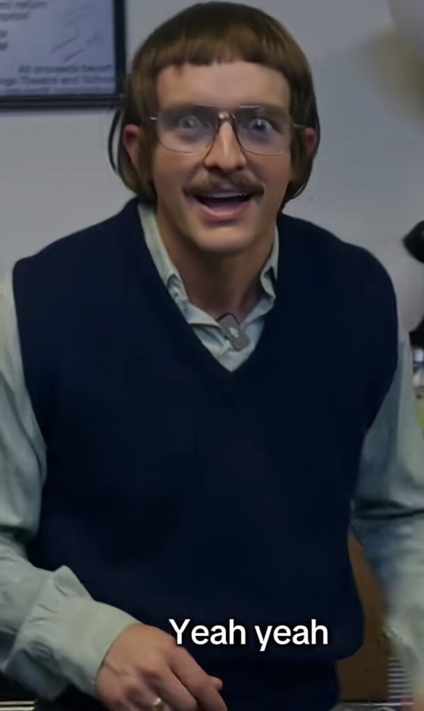Image of Chit, the viral TikTok character created by Jay Renshaw, from the “Do It Lady” skit. Chit is wearing a red sweater vest and holding a black purse.