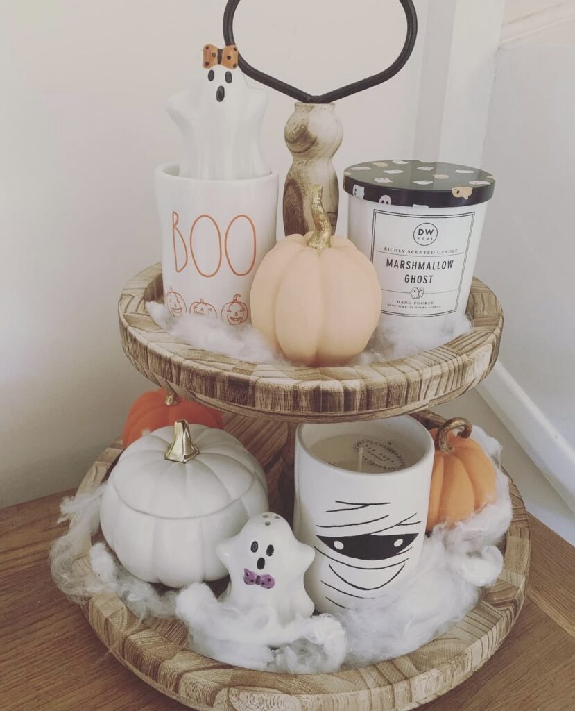 Neutral soft and cozy ghost tiered tray with cream pumpkins, wood beads, and friendly ghost decor—calm and inviting Halloween setup. Credit: magicalmooreshauls.