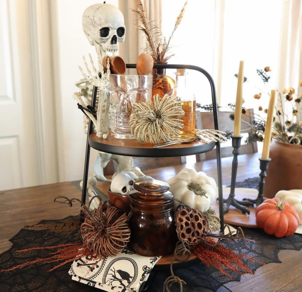 Skeleton tiered tray decorated for Halloween with skulls, skeletons, and pumpkins. Inspo for skeleton tray decor ideas at www.slowestuff.com.