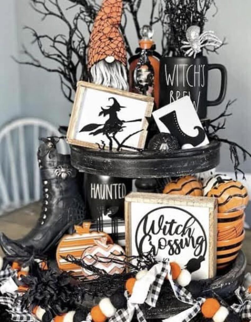 Witch themed tiered tray with striped pumpkin cutouts, tree branches, wood and ribbon accents, and a black witch hat. Credit: Catherine Moreau, www.slowestuff.com