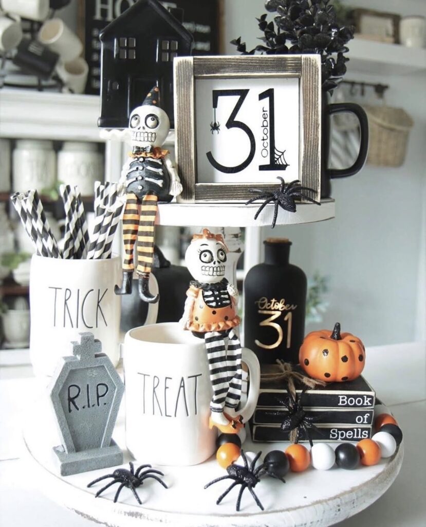 Halloween tray with skeletons, skull mugs, bone garlands, mini pumpkins, and festive banners for a spooky kitchen vibe. Skeleton tiered tray ideas at www.slowestuff.com.