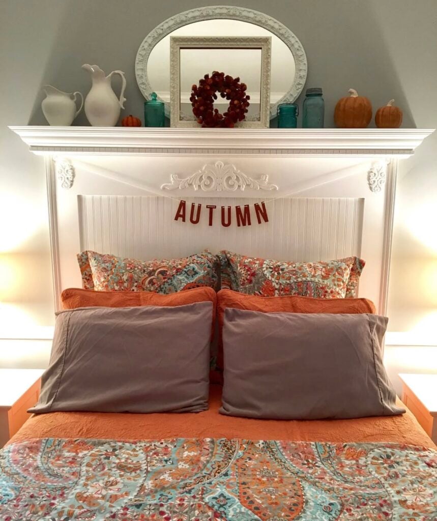 Autumn bedroom decor with paisley bedding in orange and teal, pumpkin accents, and “AUTUMN” banner above the headboard.