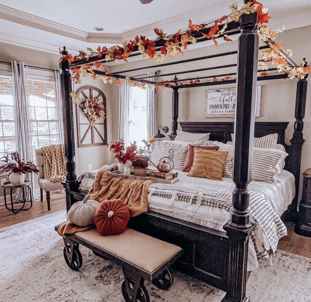 Canopy bed fall bedroom decor with leaf garland, striped bedding, warm throw blankets, and autumn-toned pillows.