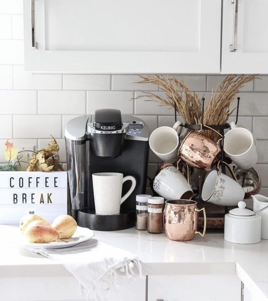 Cozy fall coffee bar in a kitchen corner with seasonal mugs, a mini wreath, and small pumpkins for autumn vibes