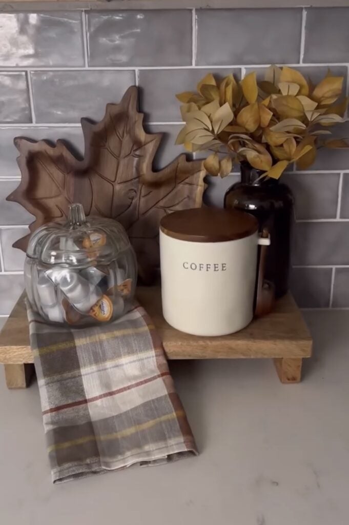Wooden coffee tray with plaid towel, glass pumpkin jar, and fall vase