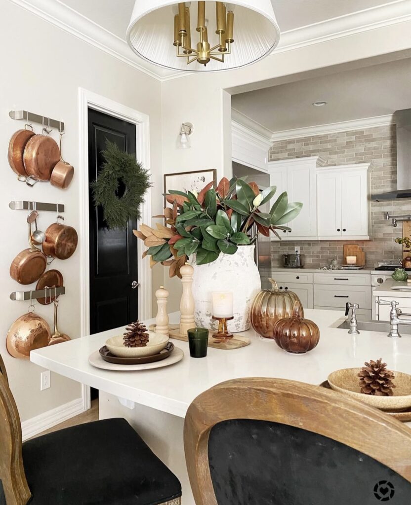 Elegant counter seating with magnolia branches, copper pumpkins, candles, and pinecones for a refined fall palette