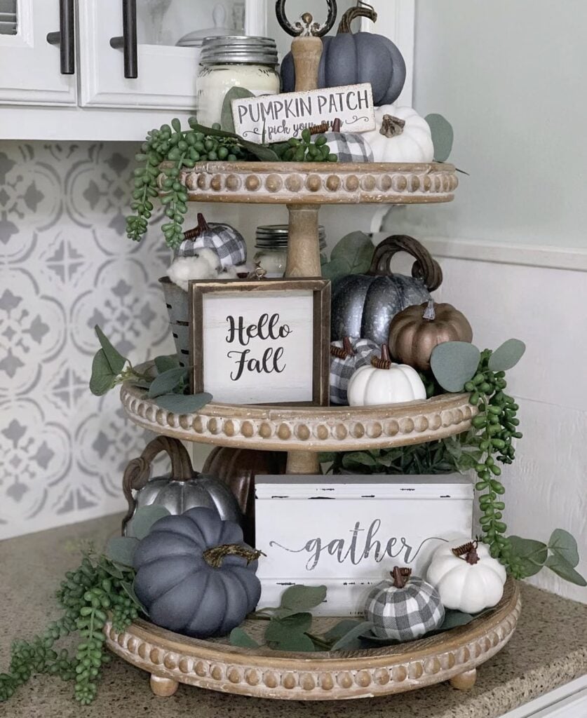 wooden three tiered tray with grey and white fall decorations with touches of greenery