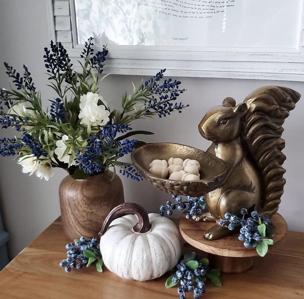 Whimsical fall entry table with brass squirrel bowl, white pumpkin, and blue florals.
