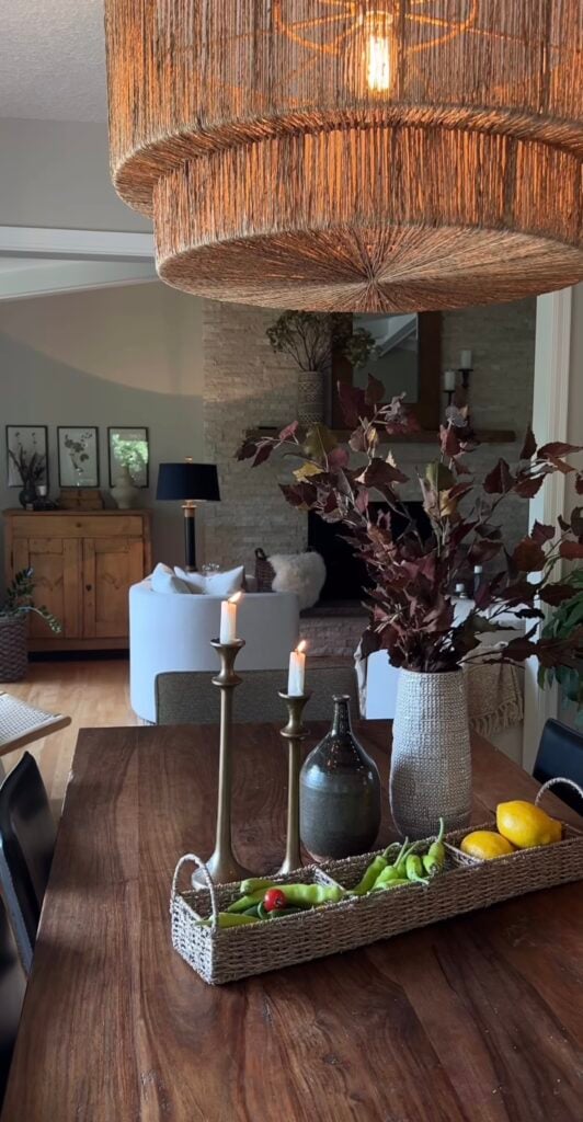fall moody decor with large vase on table with fall foliage, two candlesticks, and a rectangle bowl with peppers in it