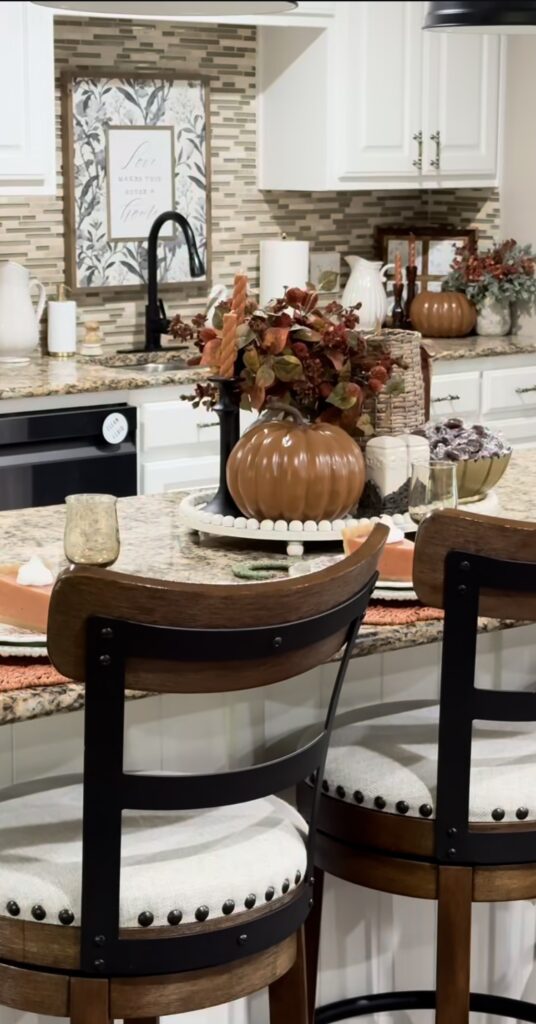 warm kitchen with white and brown features with statement tray on island with bowl filled with fall foliage, seasonal table settings