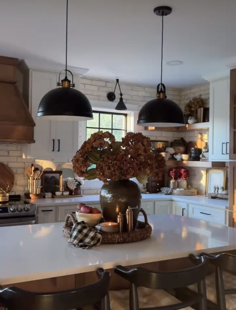 White kitchen with metal hardware in black with fall statement tray on island filled with fall hydrageas, pumpkins and candles