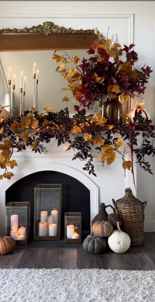 Dramatic fall mantel with brass candlesticks, amber lights, and a lush eucalyptus and maple garland.