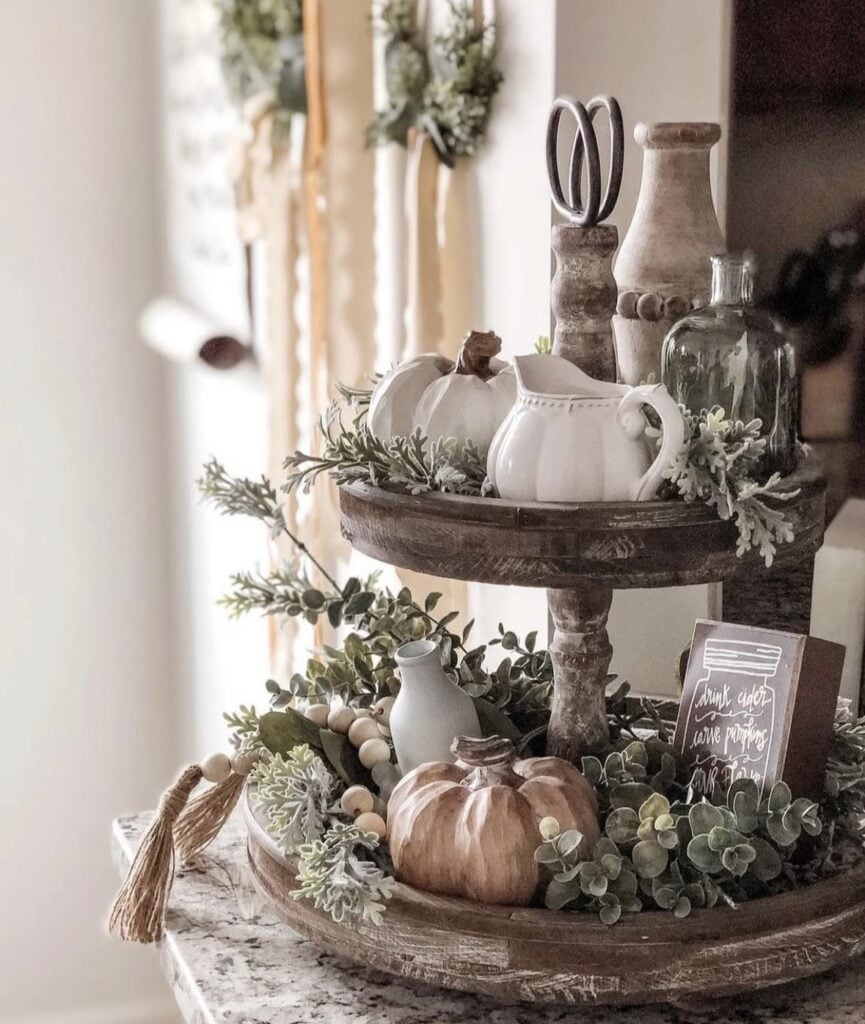 Rustic wooden tiered tray with white pumpkins, pottery and greenery