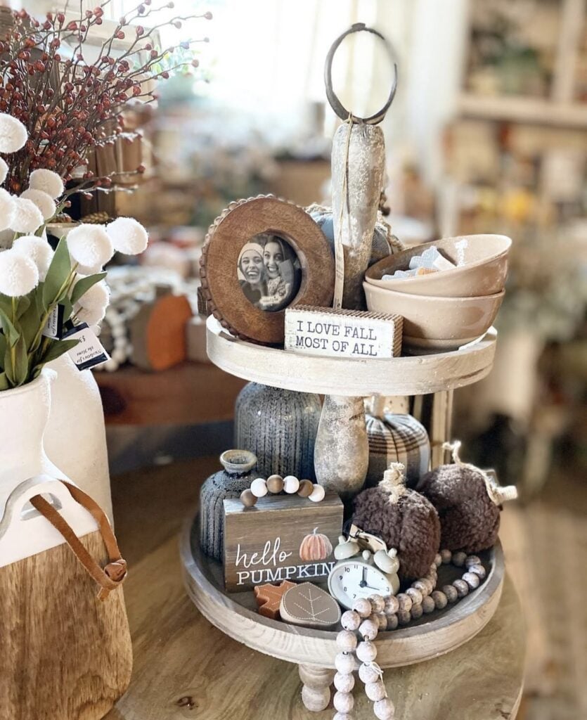 Fall tiered tray styling ideas with small pictures in frames, an alarm clock and other neutral accents