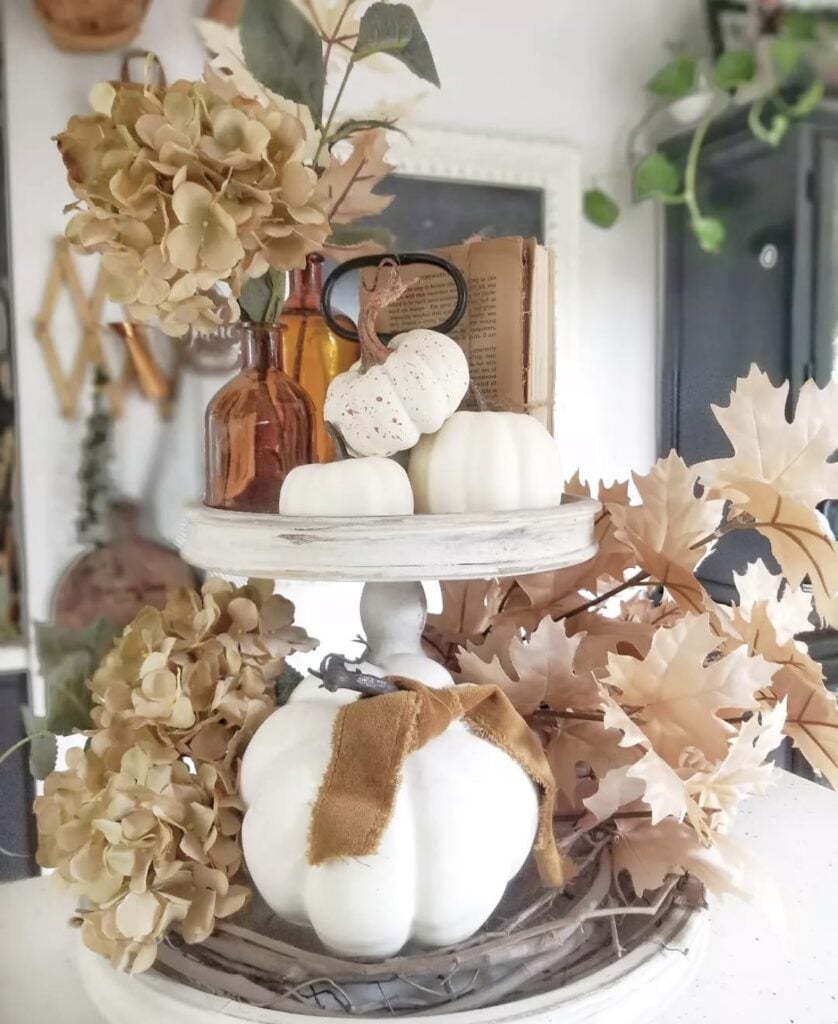 Tiered tray decor for fall with brown bottles, white pumpkins and tan foliage