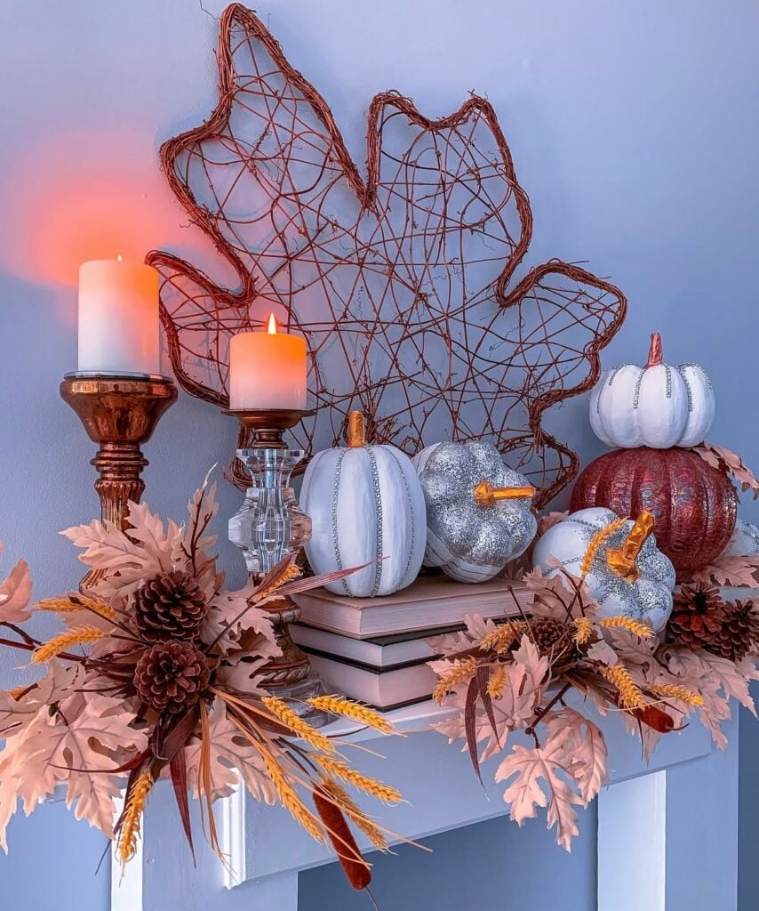 Autumn mantel with giant grapevine maple leaf, wood/glass candlesticks, stacked books, white and glitter pumpkins, and copper wheat + pinecone sprays