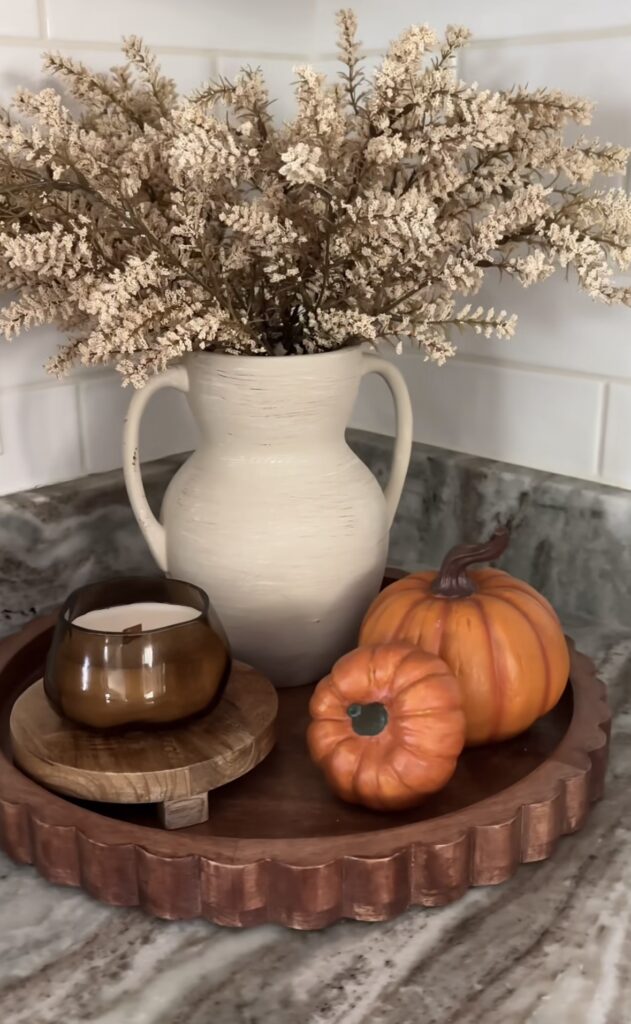 Wooden tray with vase, mini pumpkins, and amber candle
