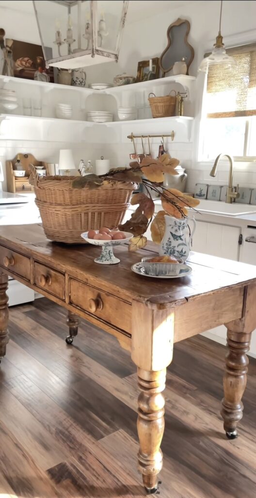 bright white rustic kitchen with small light wood table with woven basket on it and fall folliage