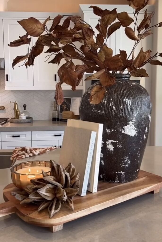 Rectangular tray with vase of brown leaves, books, and candle