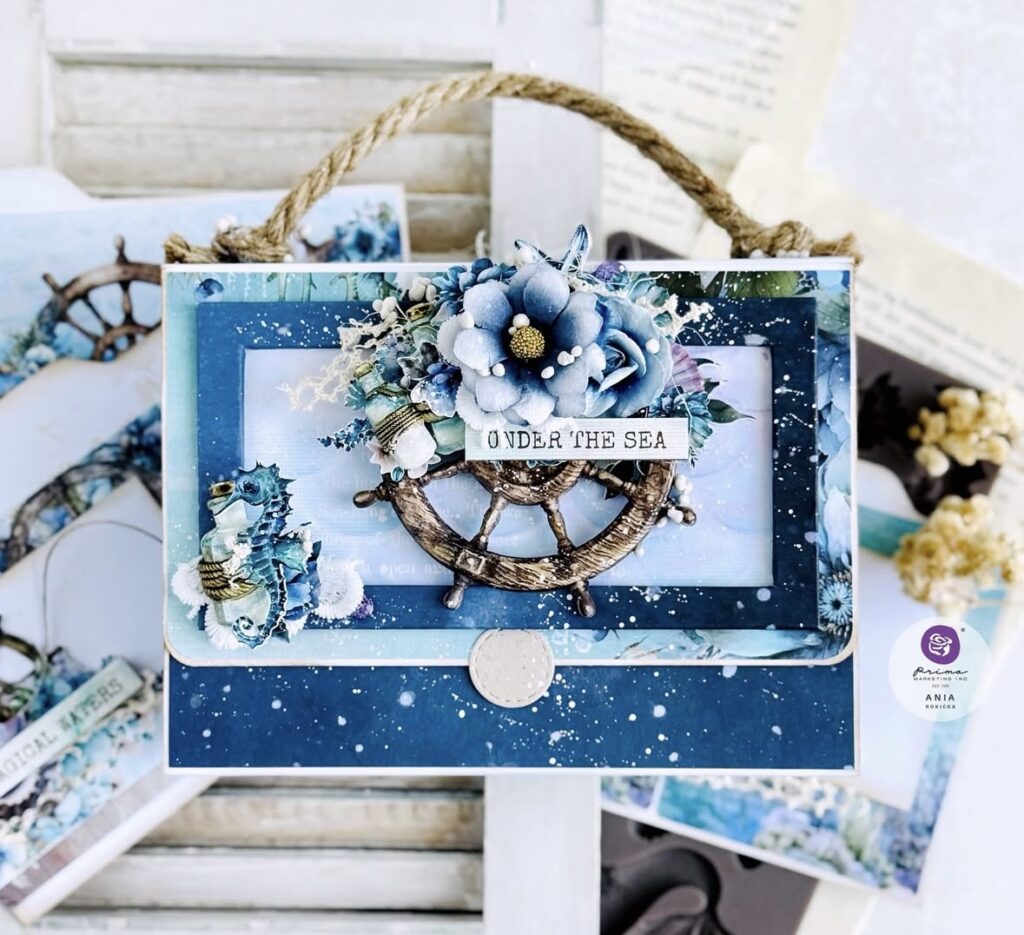 Under-the-sea journal card featuring a ship wheel, seahorse, rope handle detail, and layered blue floral