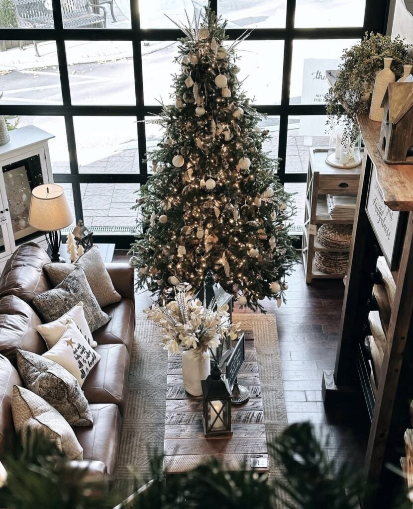 overhead view of neutral living room with grid window, leather sofa, classic tree with white lights and cream metallic ornaments