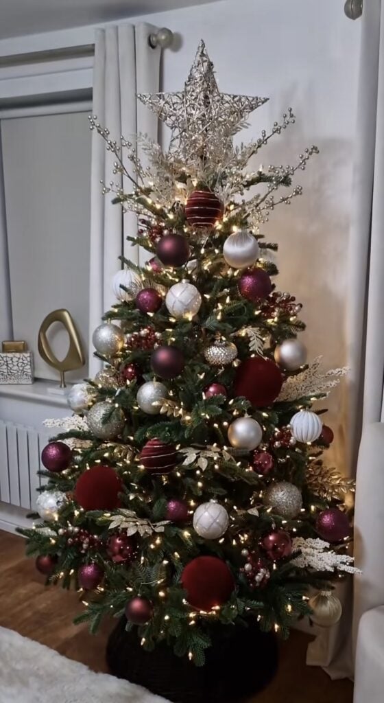 compact burgundy silver and gold tree with oversized velvet discs, textured baubles, icy sprays, wire star topper, warm lights