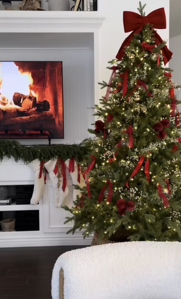 fireplace living room with classic tree, red velvet bows, baby’s breath, mantel garland, and stockings