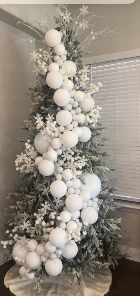 Modern minimal glam all-white Christmas tree with snowball baubles and soft white lights for a sleek gallery look.