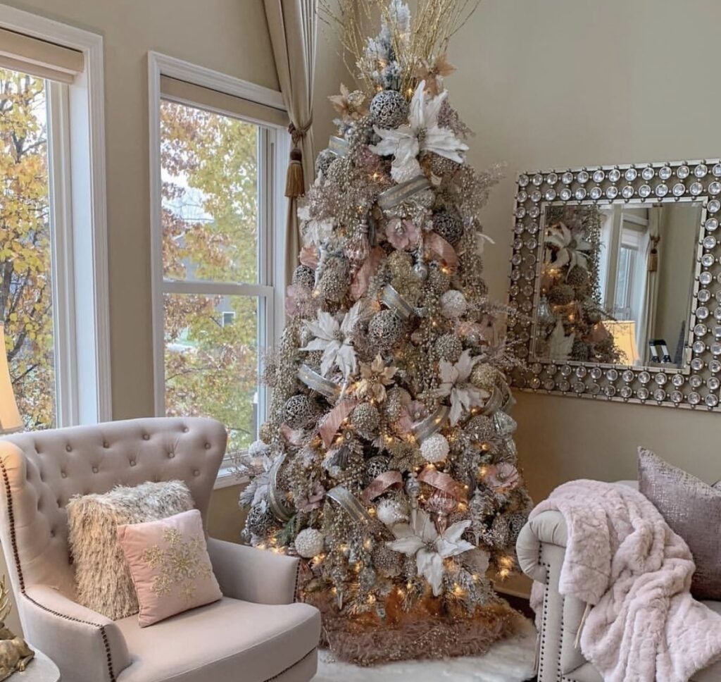Elegant blush-and-gold glam Christmas tree styled in a refined living room with satin ribbon and metallic florals.