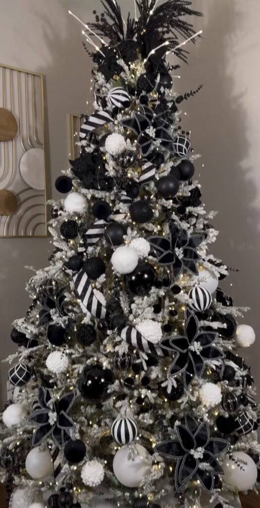 Modern monochrome glam Christmas tree in black and white with striped ornaments and graphic ribbon.