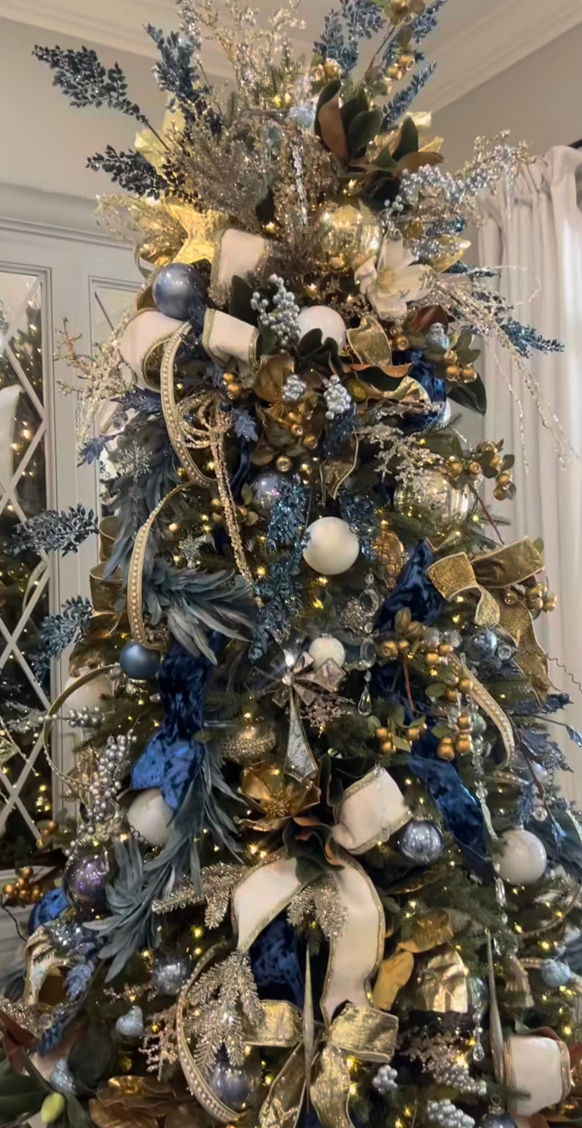 Navy-and-gold glam Christmas tree with velvet ribbons, sparkle sprays, and rich metallic décor.