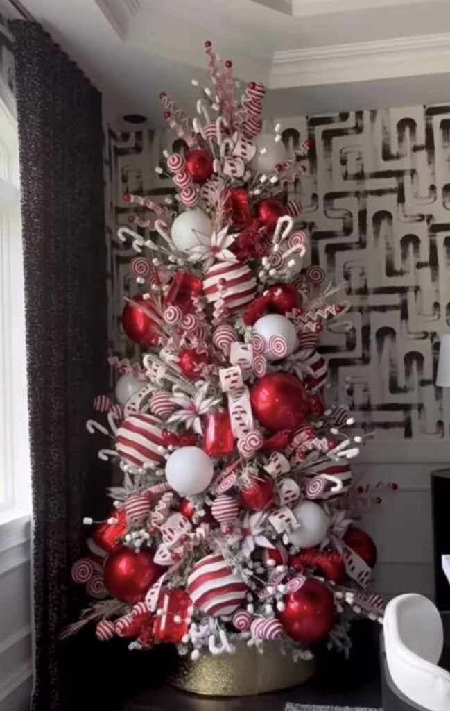Modern peppermint glam Christmas tree with oversized red-and-white ornaments and candy-stripe ribbon.
